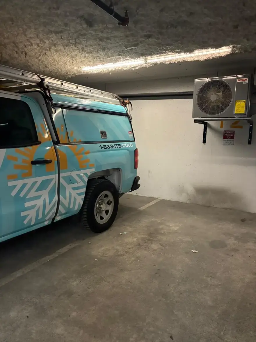 Rep-Air truck in a parkade beside a wall-mounted heat pump