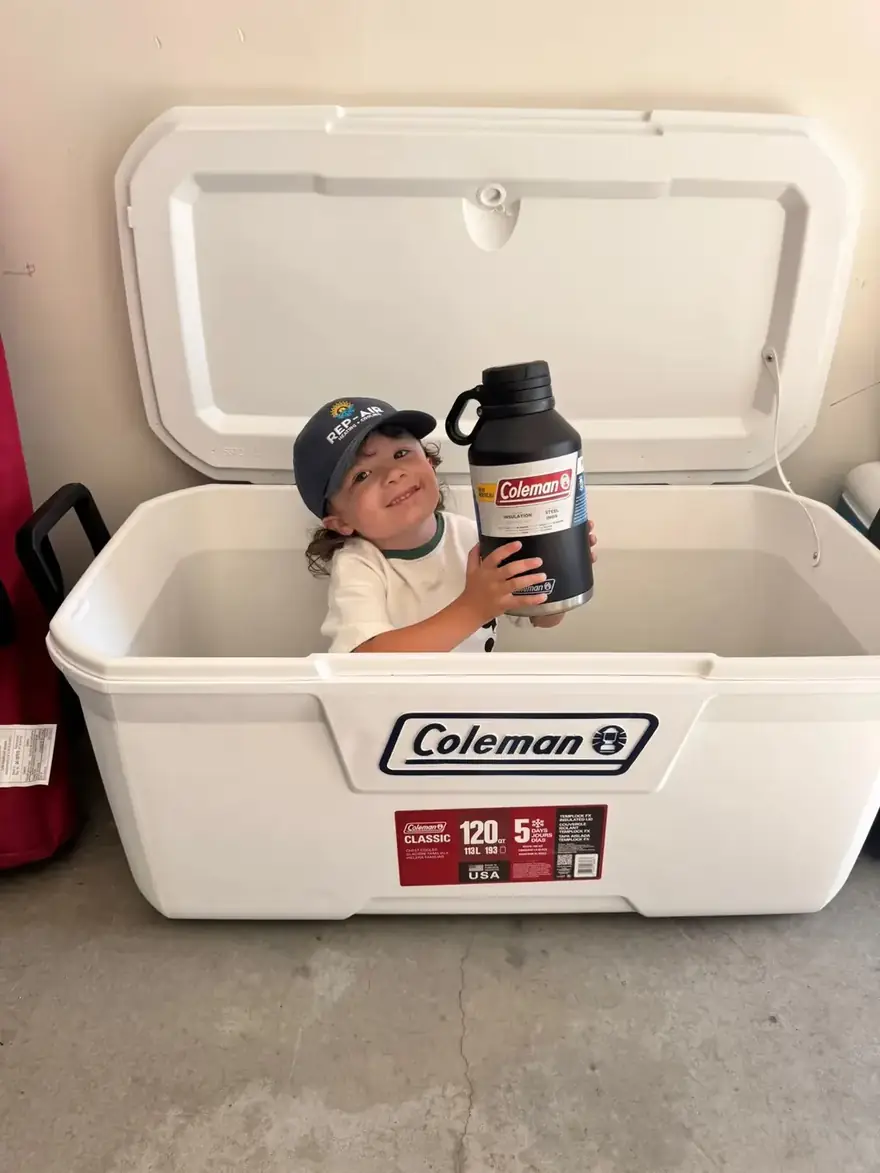 Child in a Rep-Air cap sitting in a large cooler