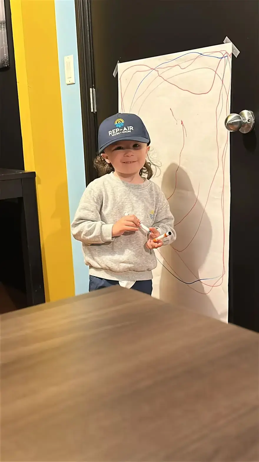 Child in a Rep-Air cap in the office