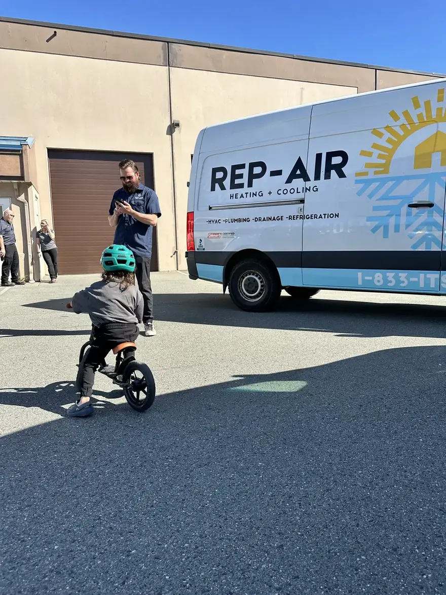 Child on a balance bike beside a Rep-Air van