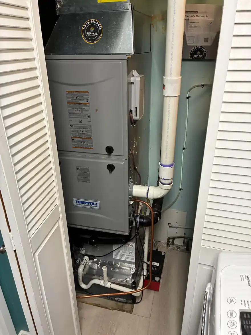Gas furnace and white PVC venting installed in a laundry closet