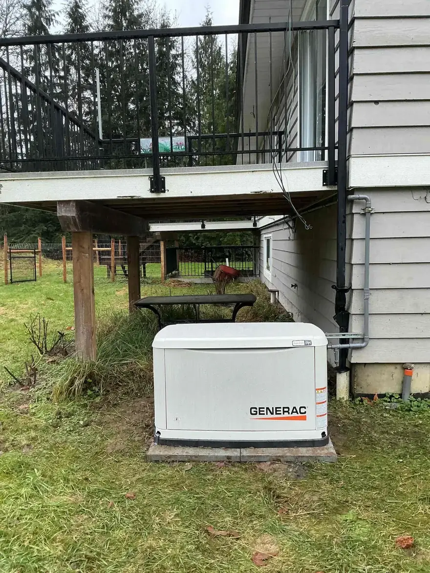 Generac standby generator beside a home with a deck