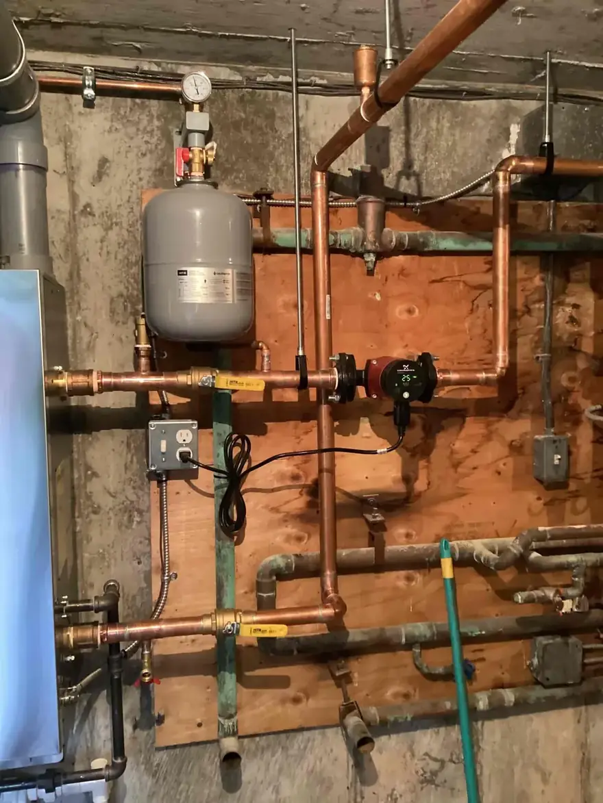 Copper hydronic piping and expansion tank on a basement wall