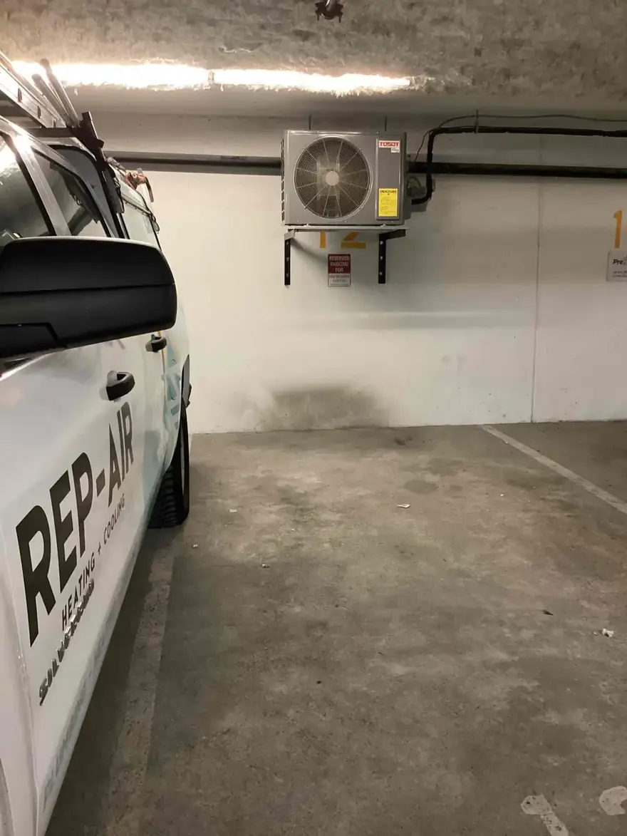 Rep-Air truck parked beside a wall-mounted heat pump in a parkade