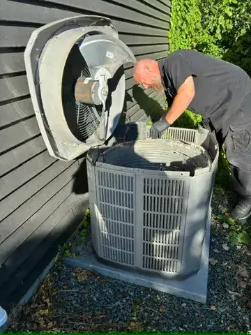 Technician cleaning the inside of a central air conditioner