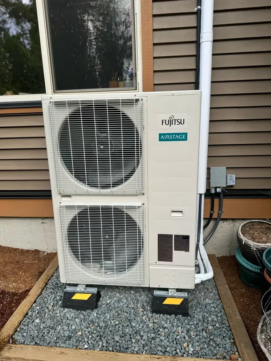Fujitsu Airstage heat pump outdoor unit on a gravel pad