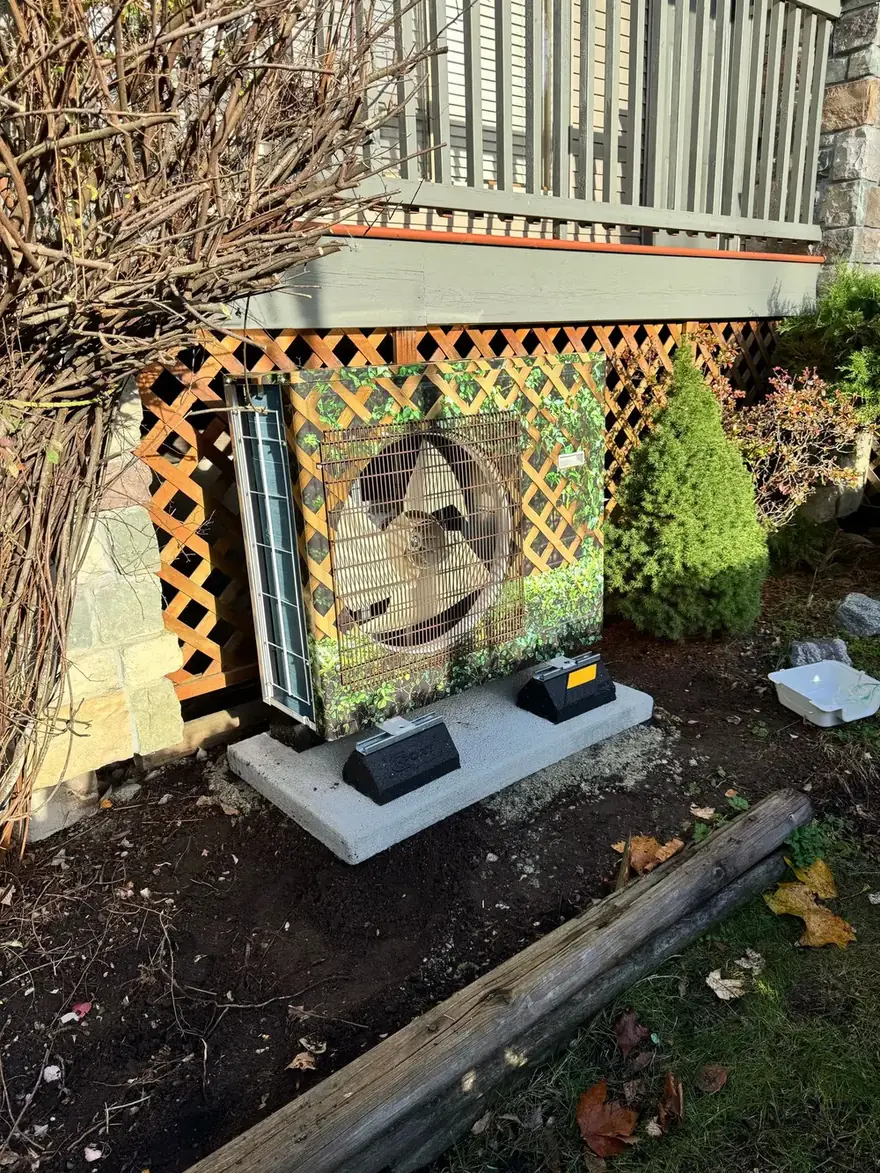 Heat pump outdoor unit on a pad below a deck