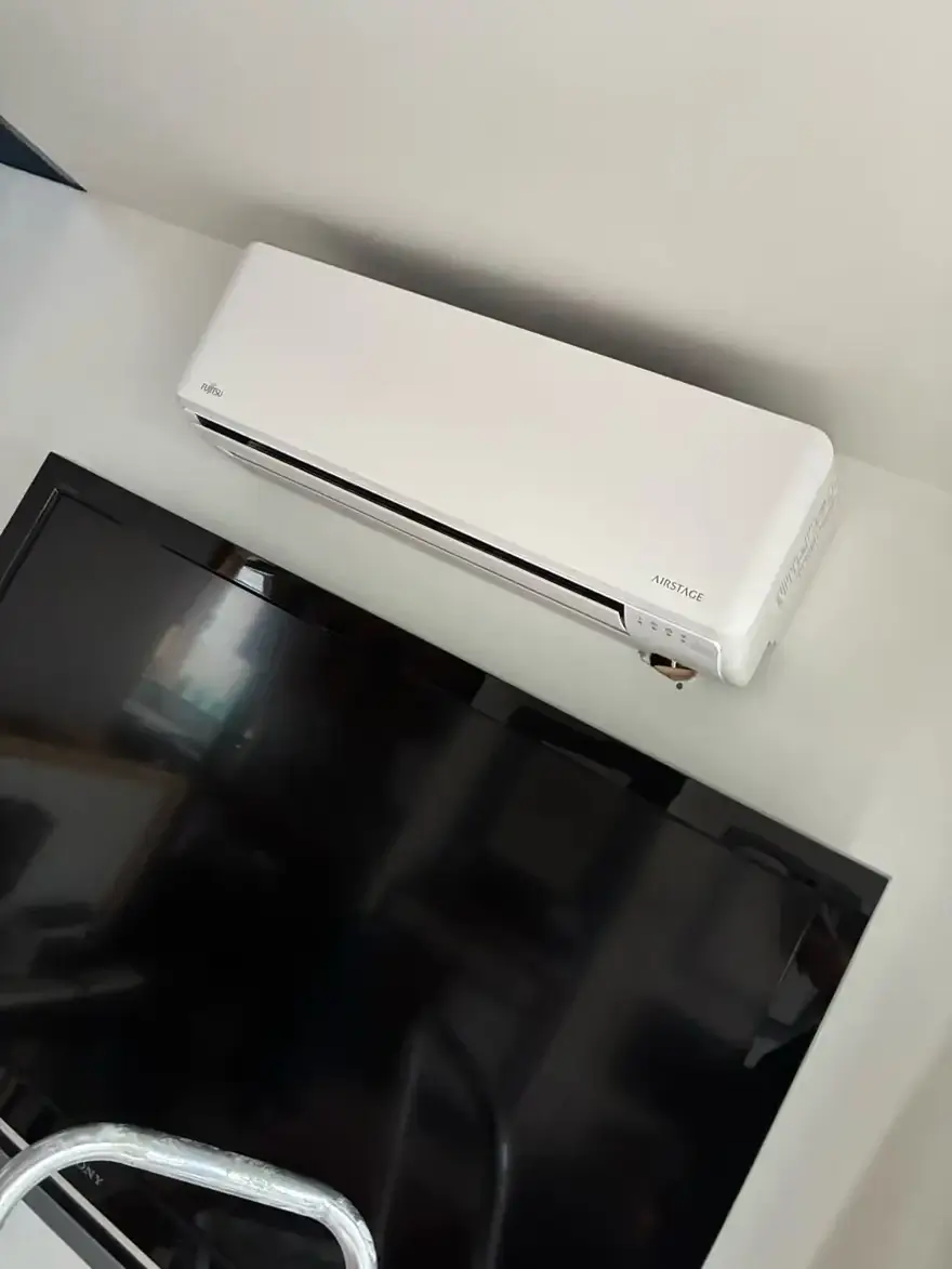 Ductless mini-split head mounted on a living room wall above a TV