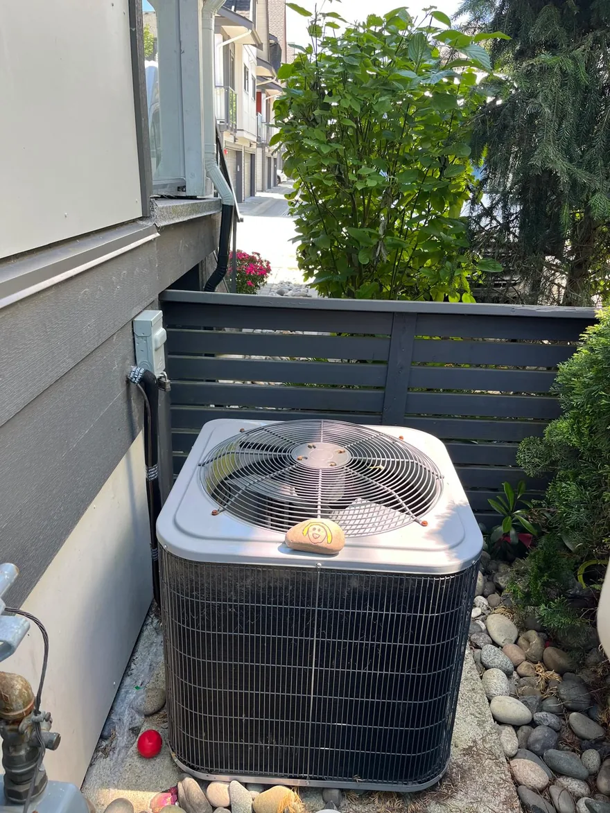 Central air conditioner condenser beside a house