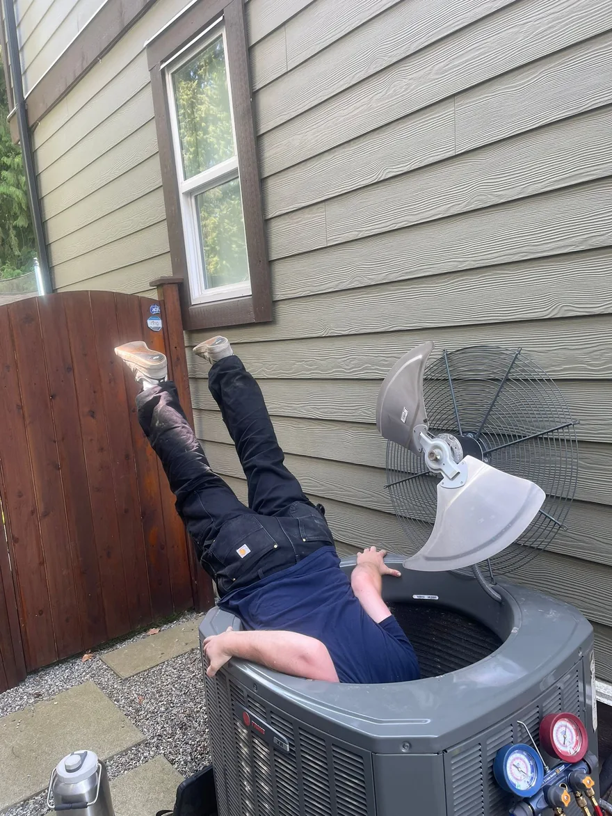 Technician reaching into an air conditioner condenser