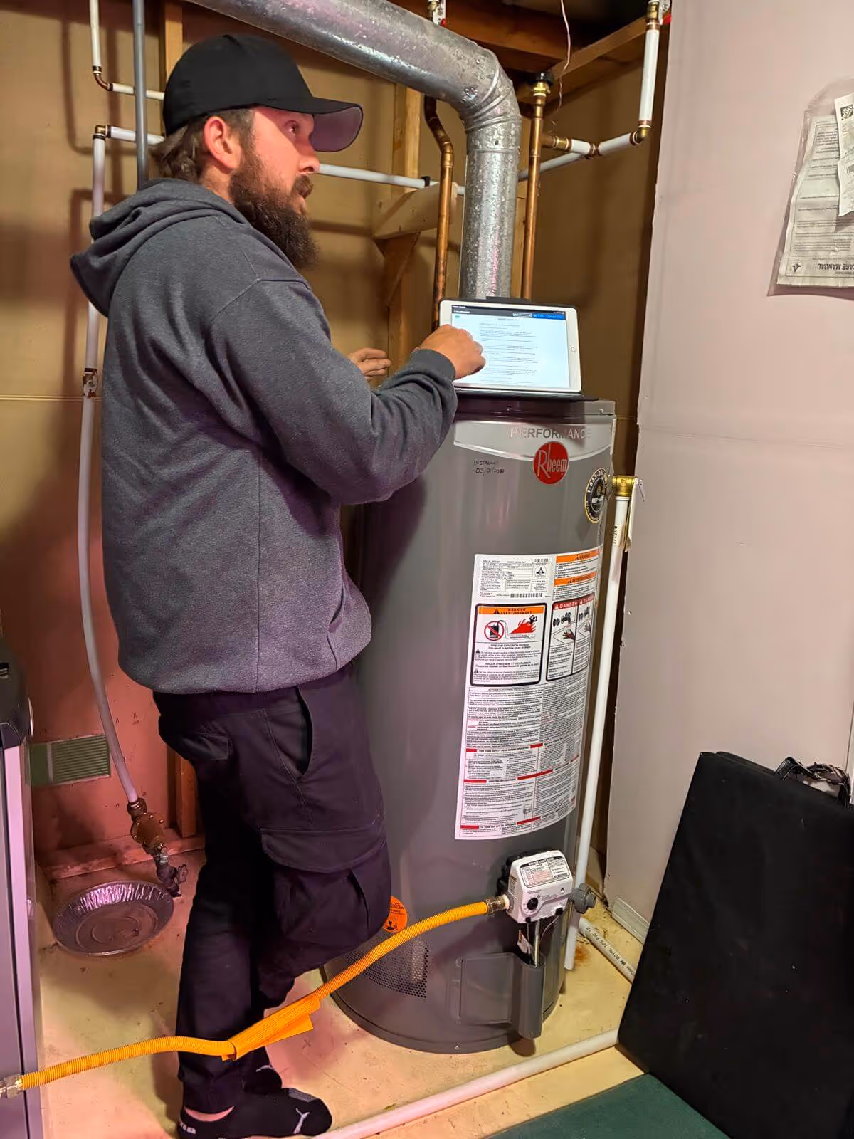 Rep-Air technician checking a gas water heater with a tablet